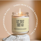 Lit candle in a jar with LET THAT SHIT GO label, featuring rose + patchouli in small batches