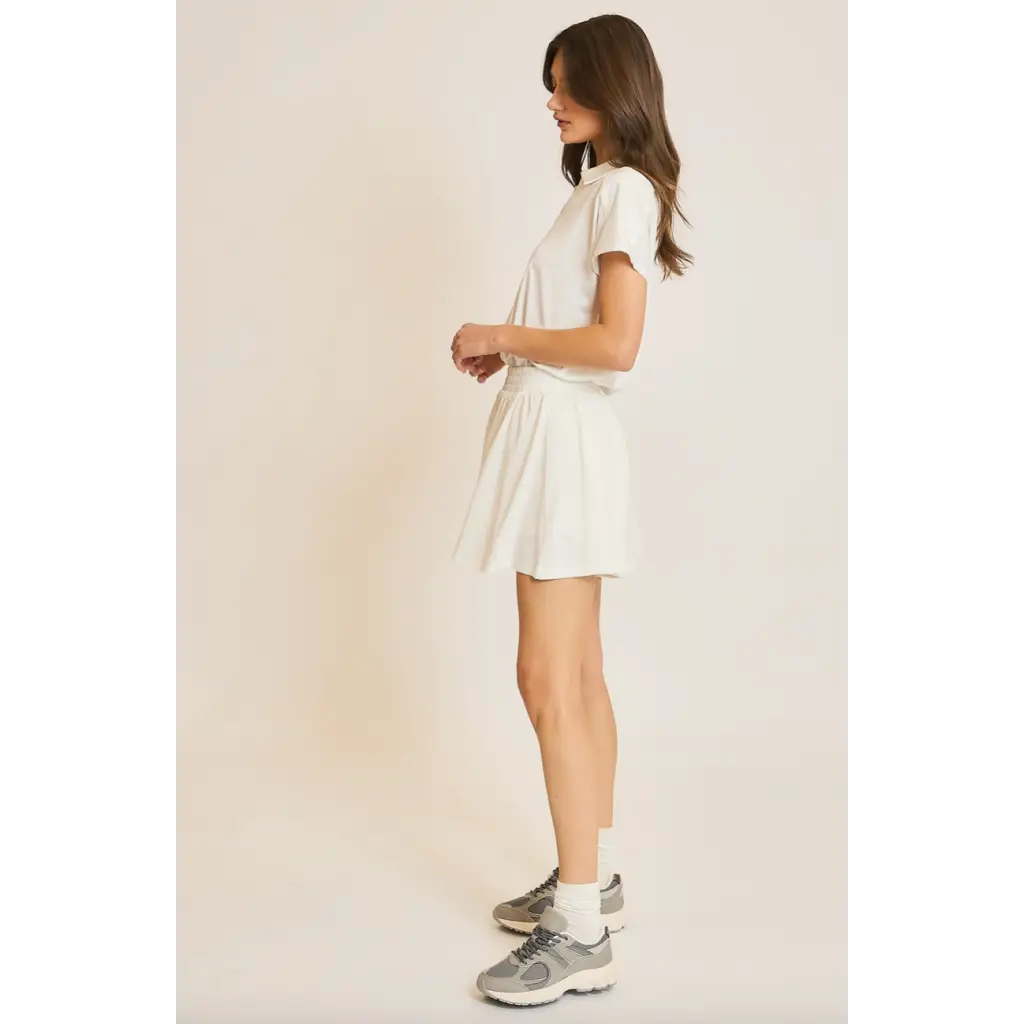 Woman in white T-shirt and skirt wearing Libby Athletic Mesh Romper showcasing lightweight athletic mesh