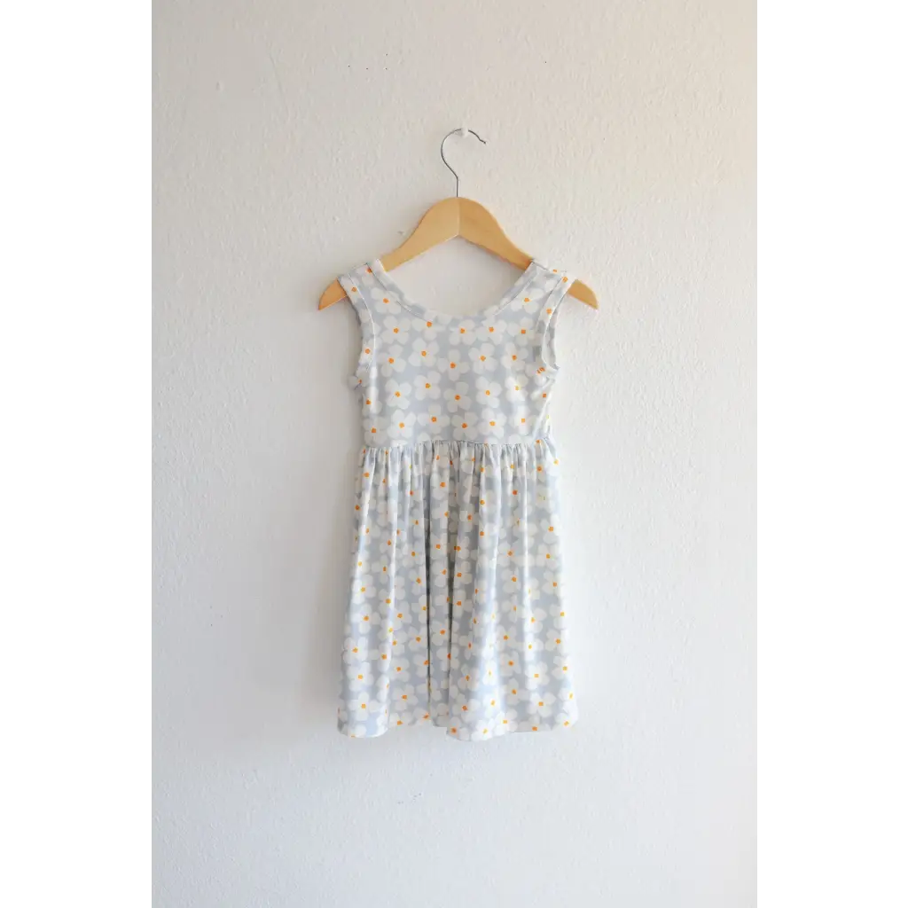 Light gray Libby Twirl Dress with daisy print hanging on a wooden hanger