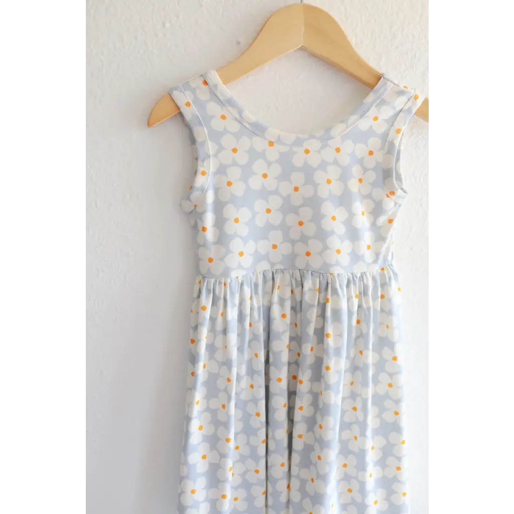 Light blue Libby Twirl Dress with daisy print hanging on wooden hanger for everyday fun