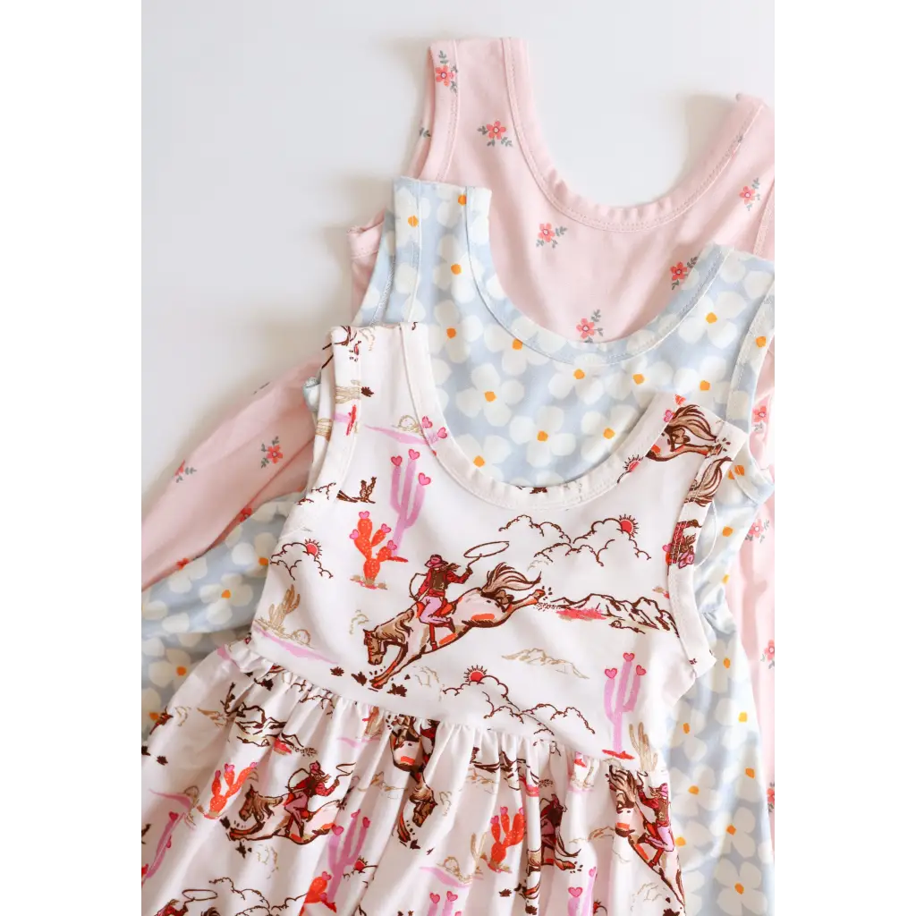 Three stylish sleeveless Libby Twirl Dresses in pink and white floral patterns
