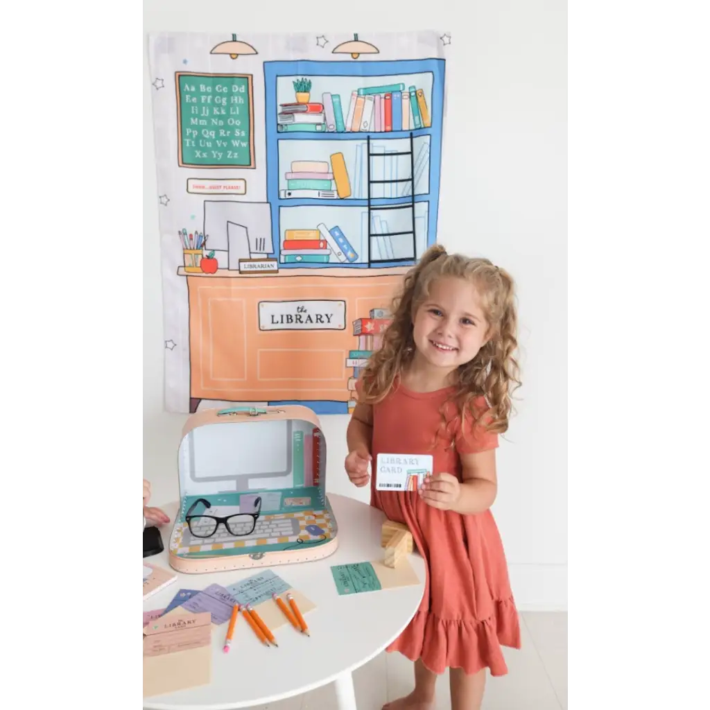 Child in a coral dress enjoying imaginative fun with a Library Play Kit