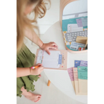 Someone in a green dress organizing papers at a desk with the Library Play Kit