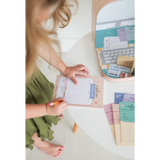 Someone in a green dress organizing papers at a desk with the Library Play Kit