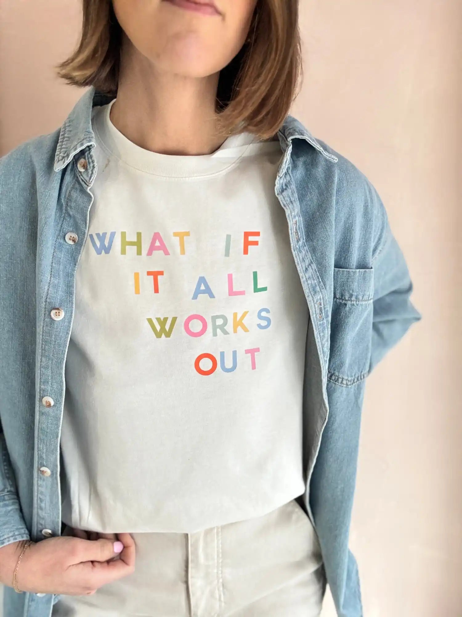 A light-colored short-sleeved t-shirt with colorful text, worn under an open denim long-sleeved shirt.