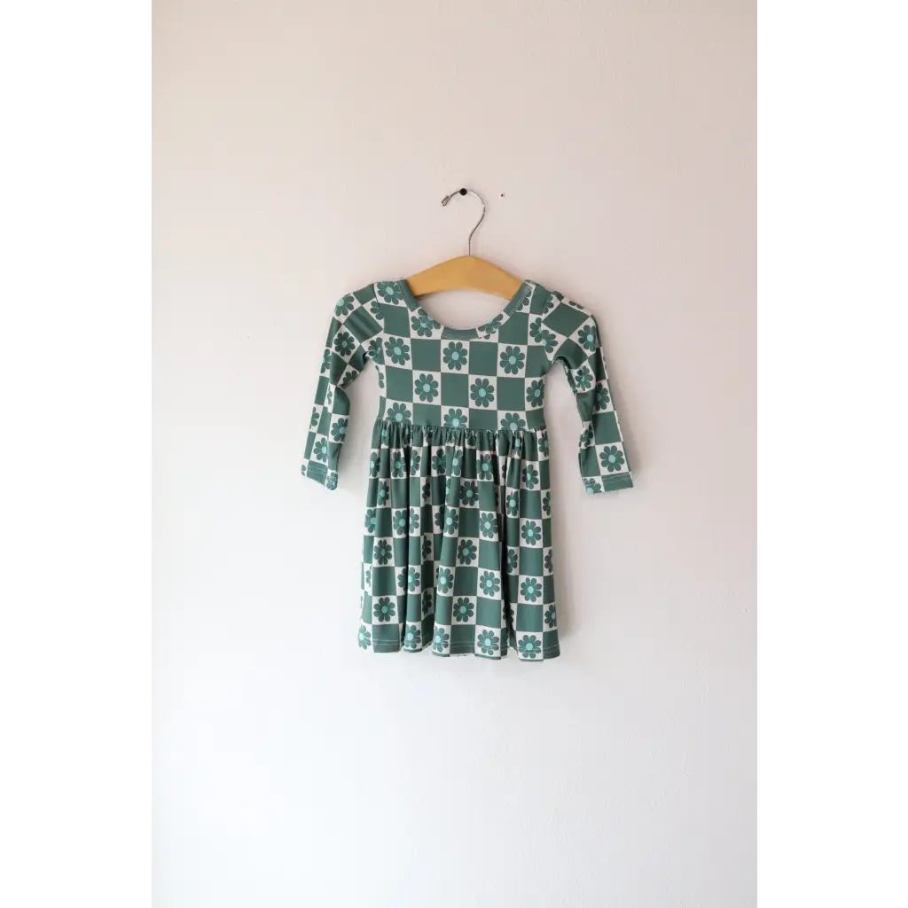 Green and white Lily Flower Check Long Sleeved Twirl Dress hanging on a wooden hanger