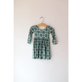 Green and white Lily Flower Check Long Sleeved Twirl Dress hanging on a wooden hanger