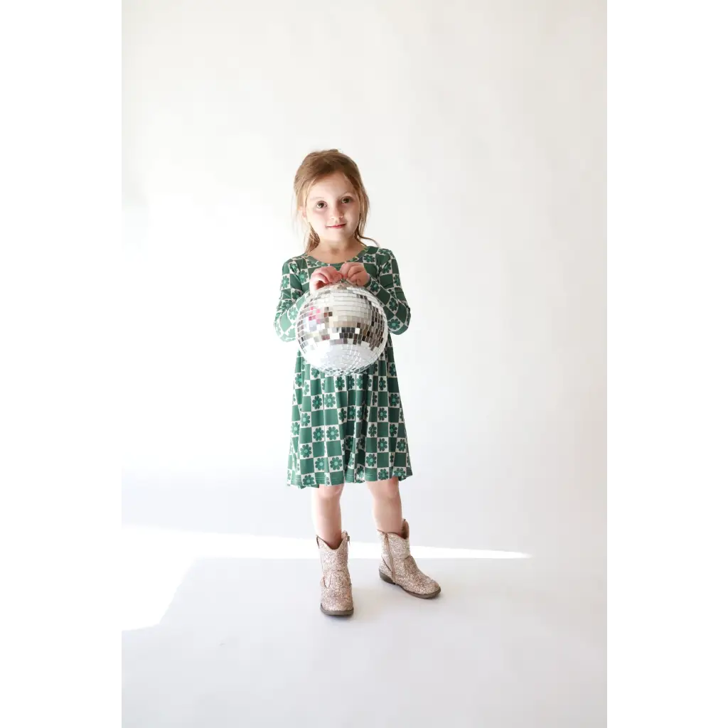 Child in a Lily Flower Check Long Sleeved Twirl Dress and beige boots, looking cute