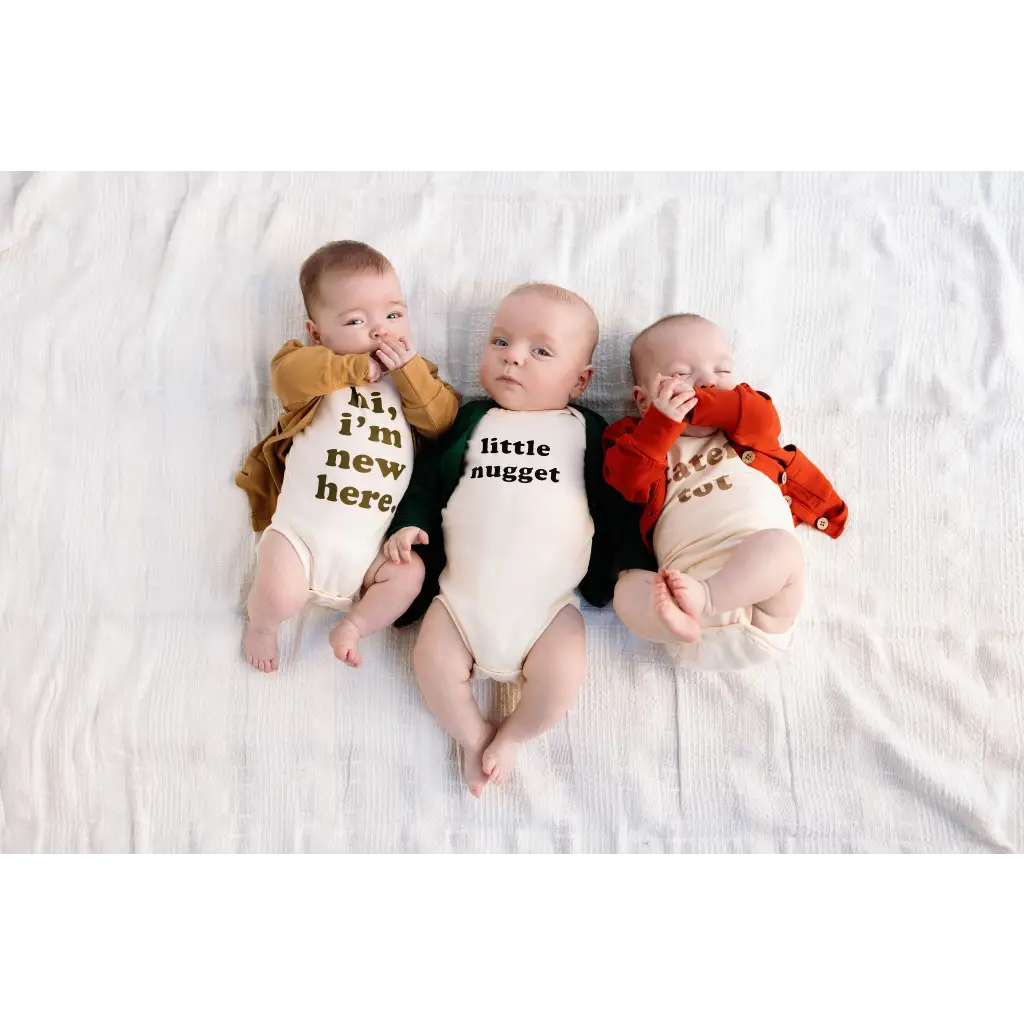 Three babies in Nugget Organic Cotton Onesies with fun text messages, perfect for 3mo fits