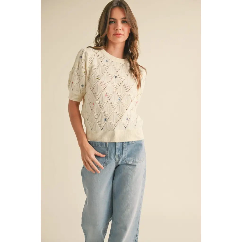 Woman wearing Liv Pointelle Knit Sweater with floral embroidery and light blue jeans