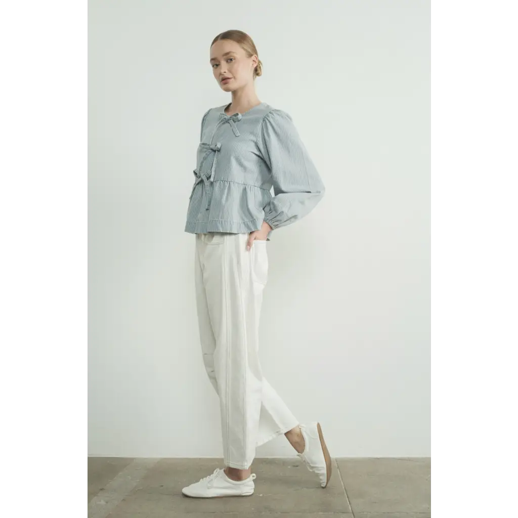 Casual outfit with sage green blouse, white trousers, and long sleeve denim bow sneakers