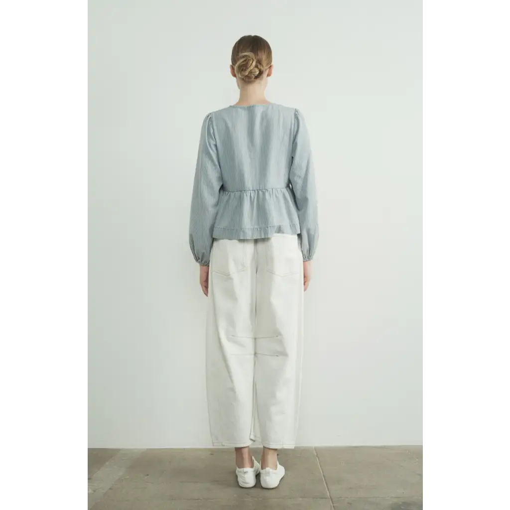 Back view of light blue peplum blouse with long sleeve denim bow and white pants outfit