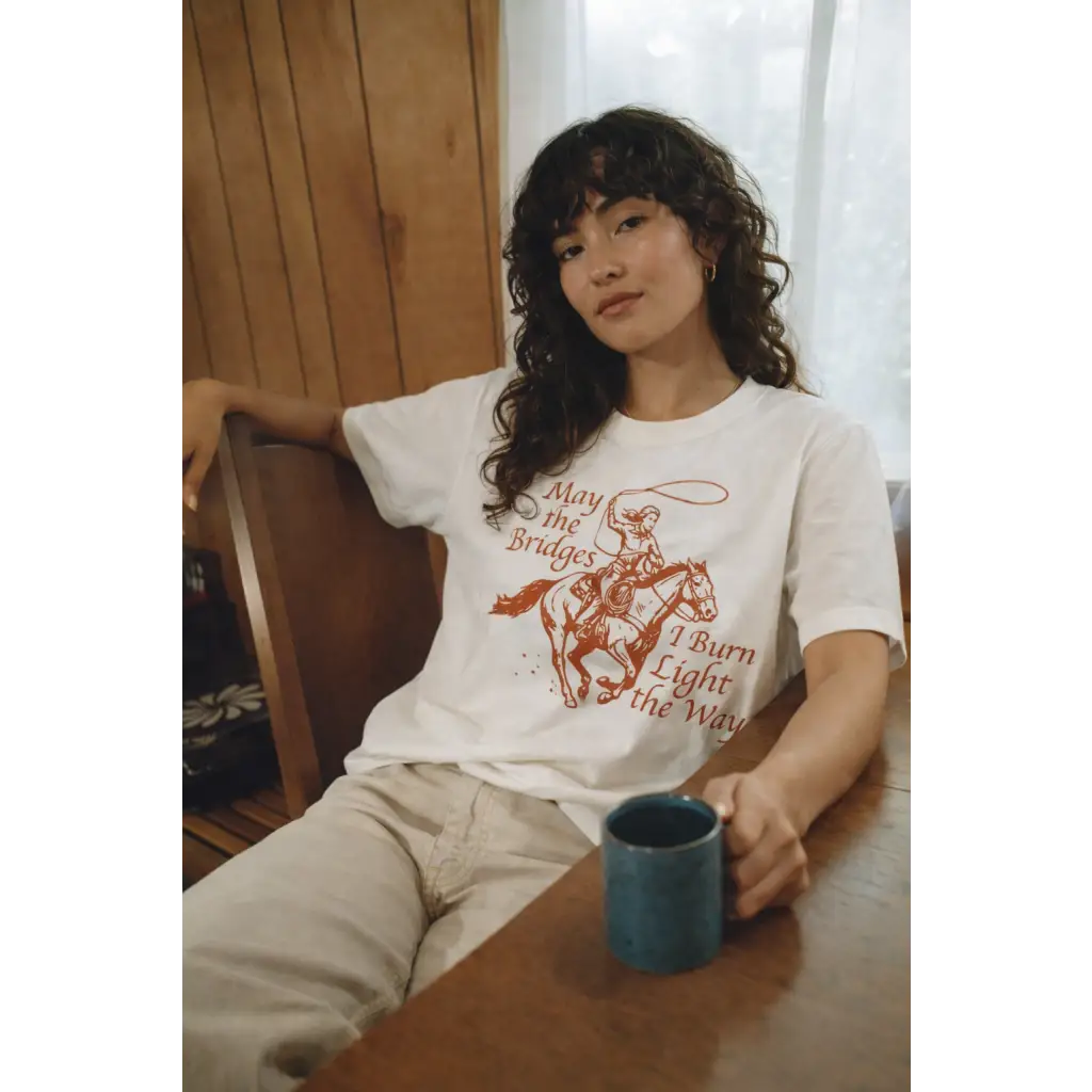 Oversized unisex tee with orange cowboy print and May the Bridges I Burn Light the Way text