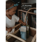 Child in white shirt and turquoise headband exploring vinyl records with mini cozy blanket