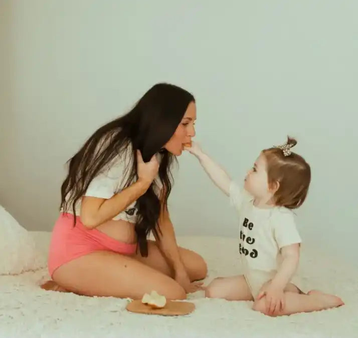 A mother and baby sharing a playful moment together on the floor.