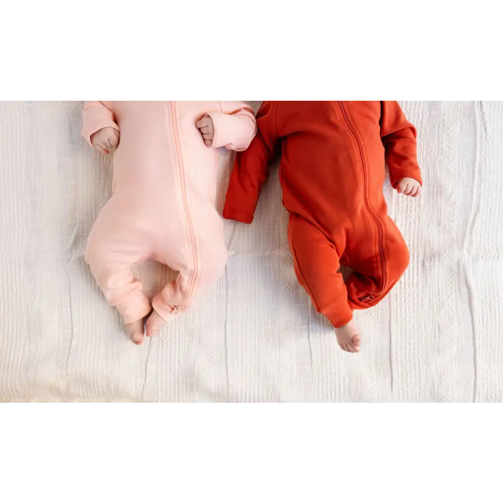 Two babies in pink and red onesies snuggled in a Peace Signs Camp baby gift box