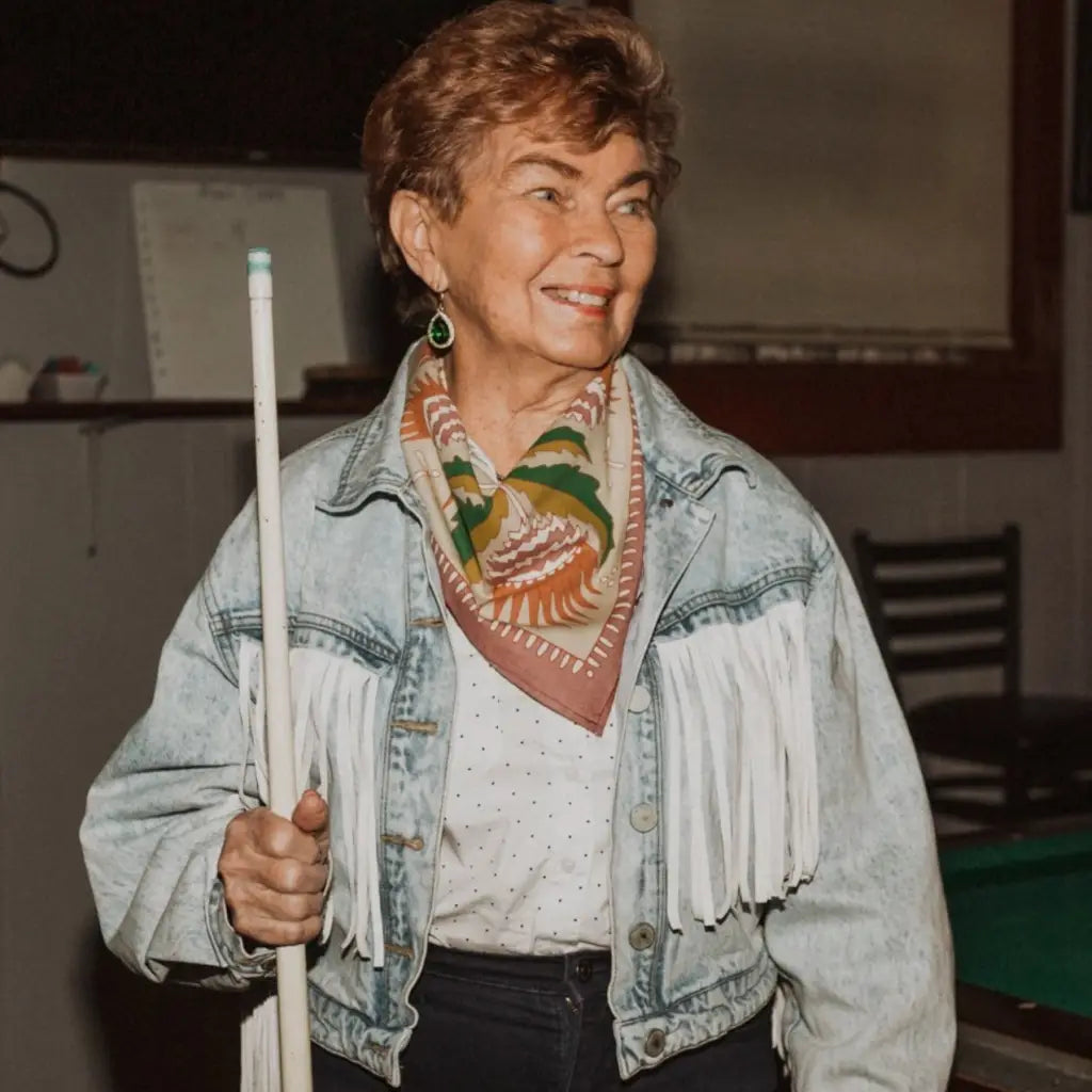 Person in fringed denim and floral Martha Bandana with Polished Prints holding a pool cue