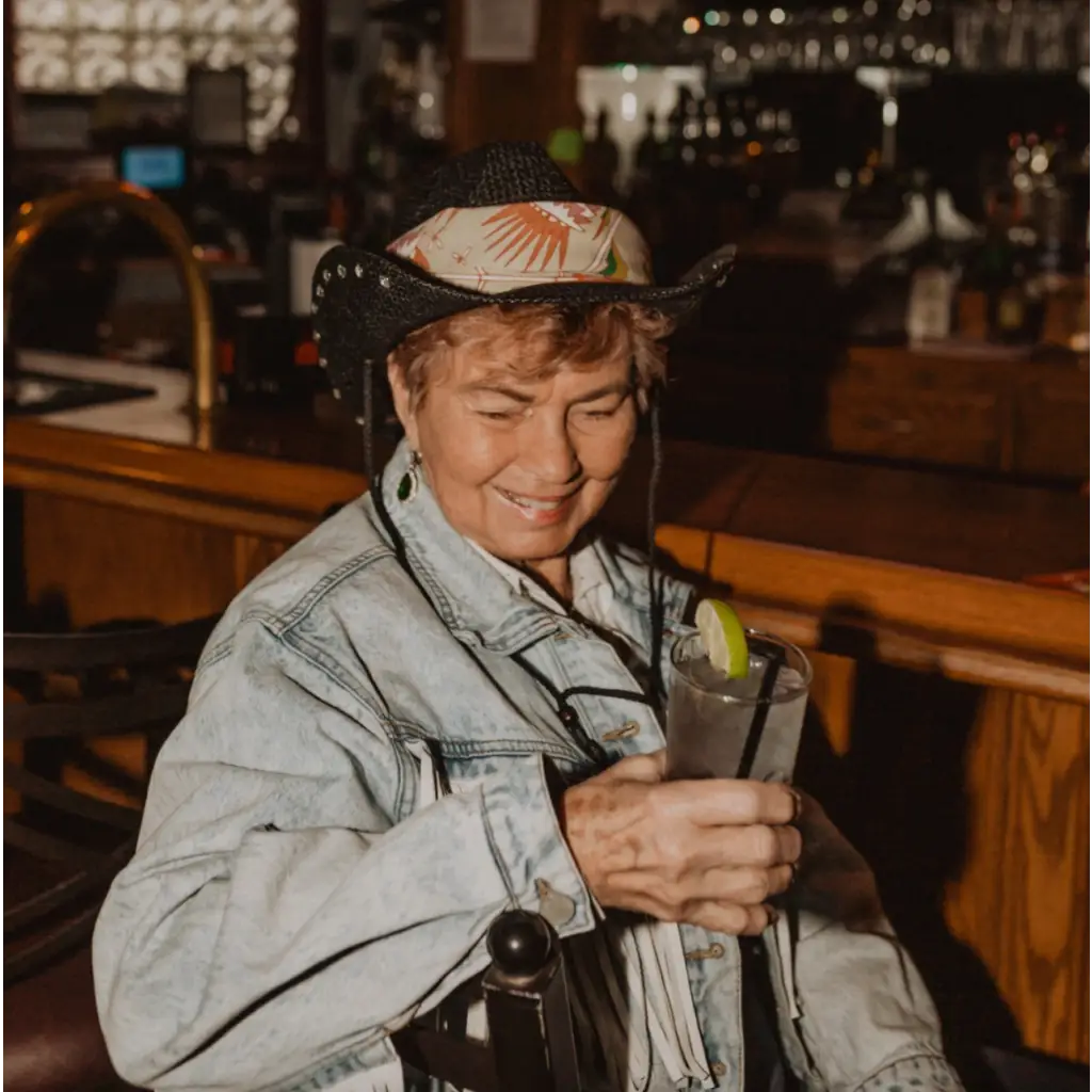 Someone in a denim jacket and cowboy hat enjoying a drink, featuring the Martha Bandana