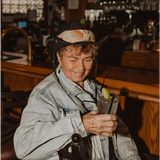 Someone in a denim jacket and cowboy hat enjoying a drink, featuring the Martha Bandana