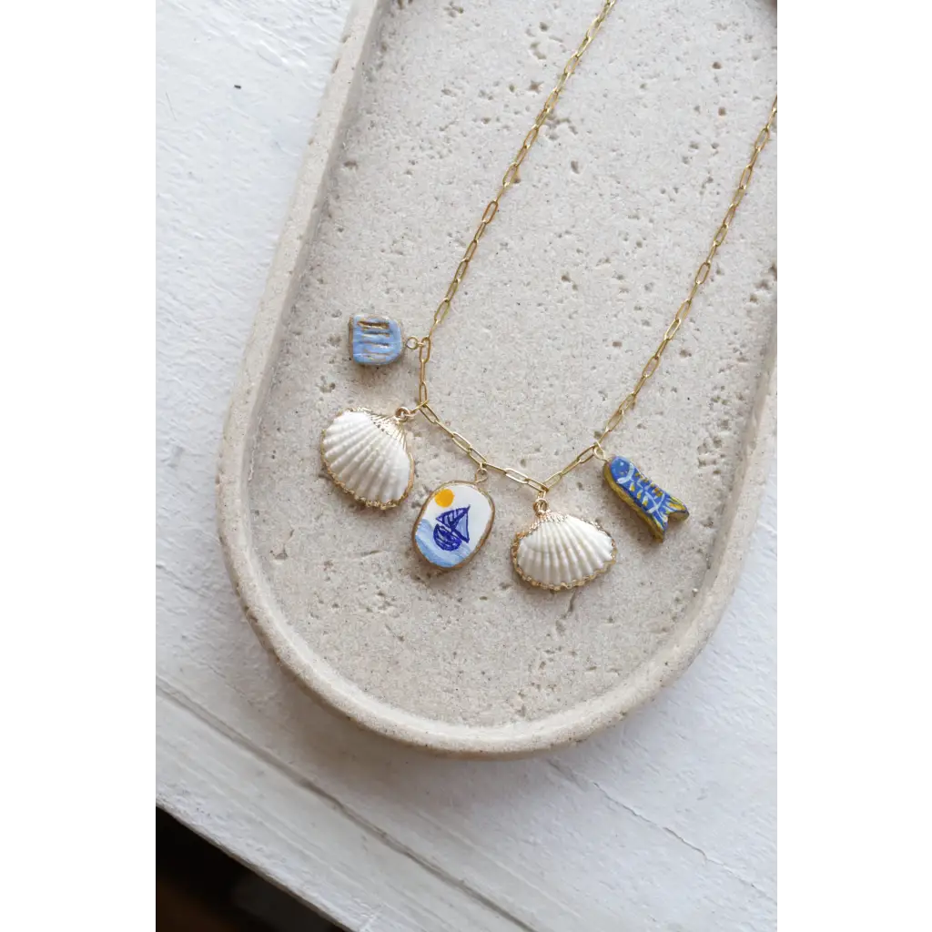 Gold chain necklace with clay charms like shells, sailboat, fish, and good luck symbols