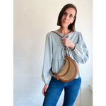 Woman with a Nora Saddle Adjustable Crossbody Bag featuring polished prints and a crescent shape