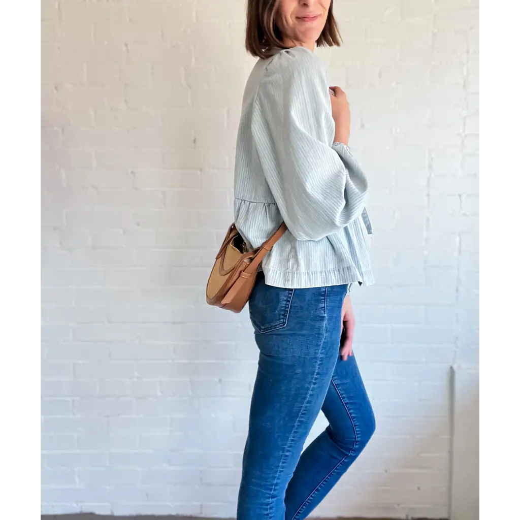 Woman in a striped blouse and jeans flaunting the Nora Saddle crossbody bag