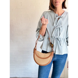 Tan half-moon Nora Saddle Crossbody Bag showcasing stylish polished prints