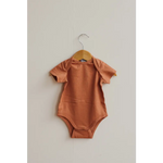 Terracotta baby bodysuit in Toasted Nut on a wooden hanger, made from organic cotton