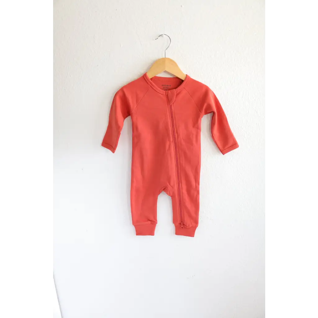 Coral Organic Cotton Baby Zipper Sleeper hanging on wooden hanger for cozy comfort