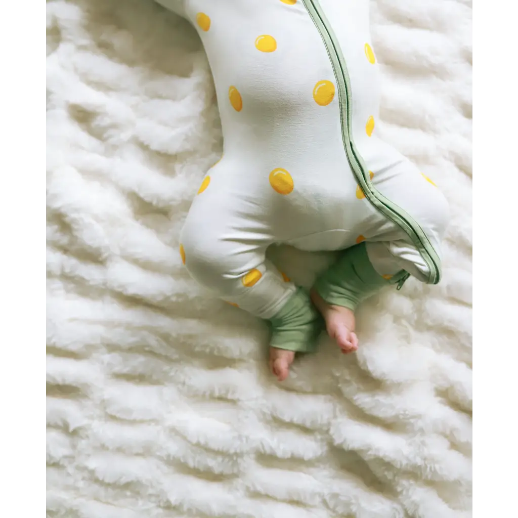 Baby rocking a white polka dot onesie with green shorts in an Easy Bamboo Sleeper