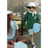 Two people on a tennis court with kids embroidered polo and pickleball paddles