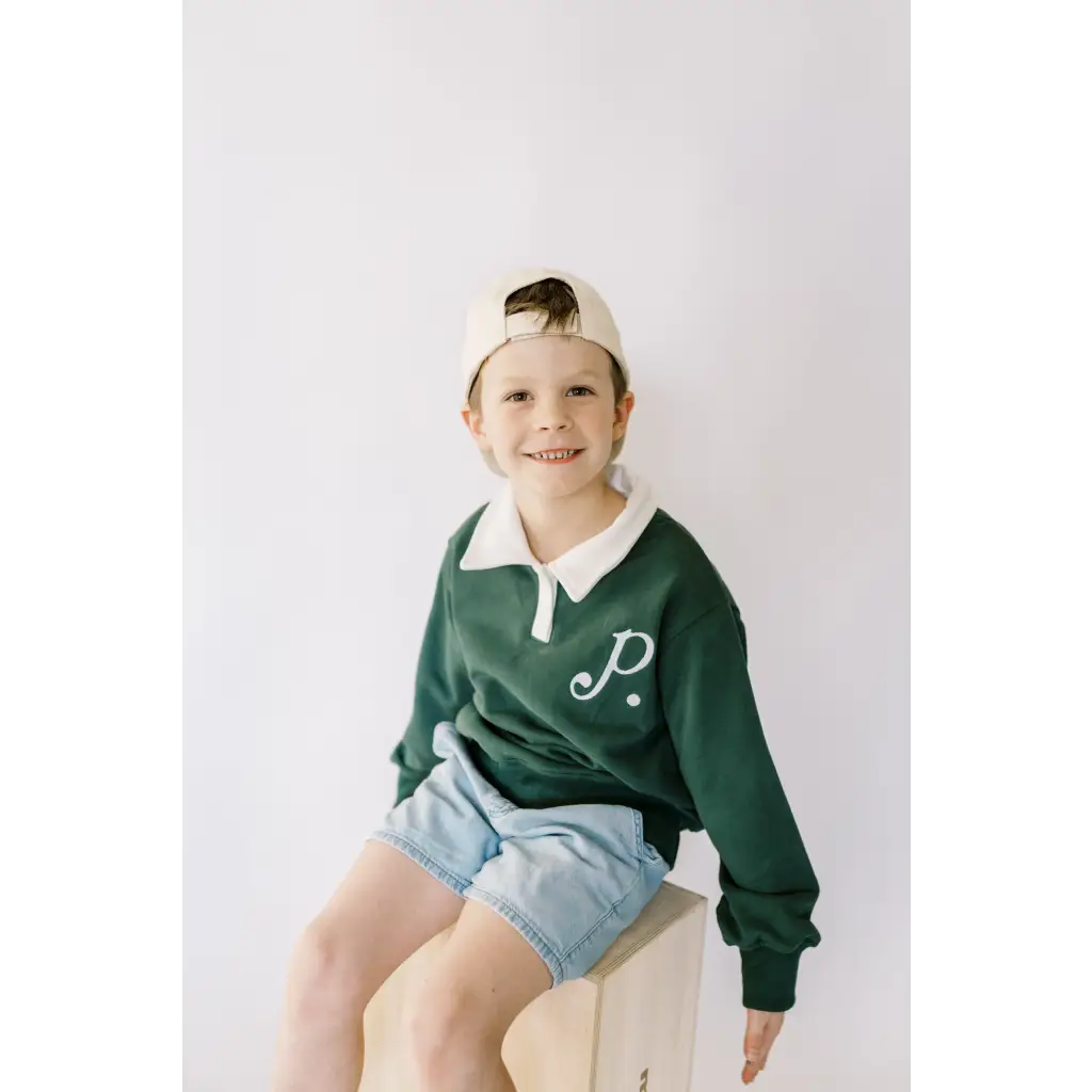 Child in a green embroidered polo pullover and denim shorts for stylish comfort