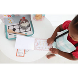 A kid using the Pasta Shop Play Kit for pretend play while drawing nearby a stovetop