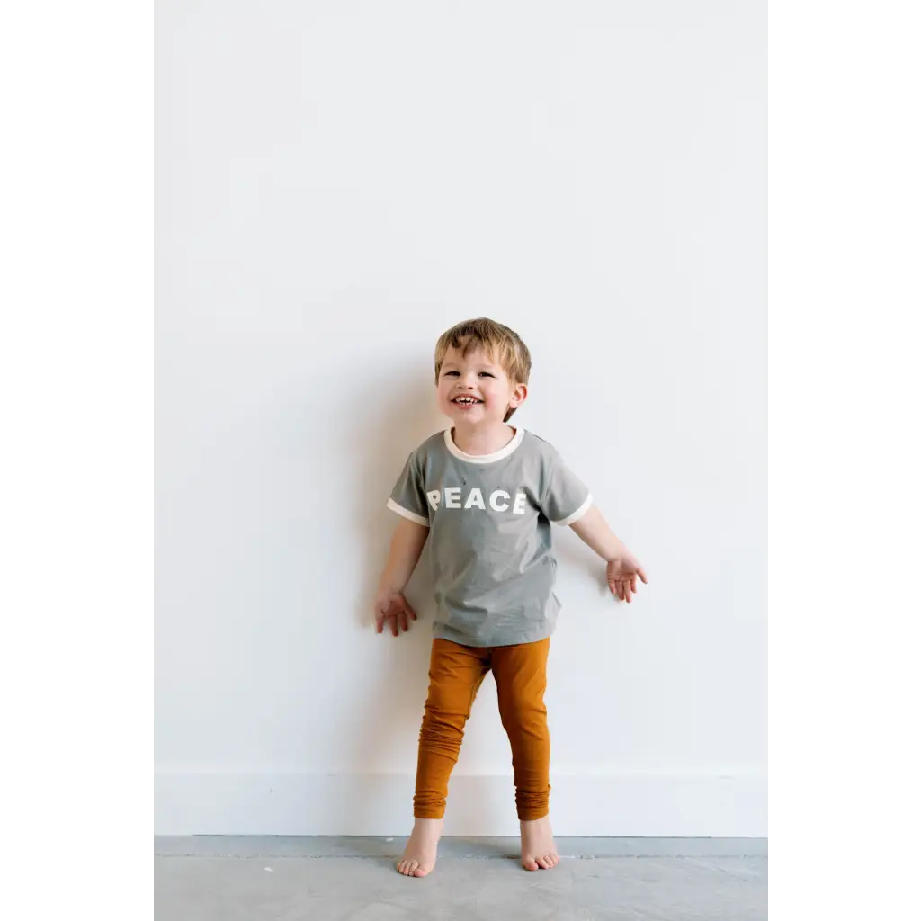 Barefoot kid in gray PEACE everyday ringer tee and orange pants, perfect for fun times