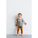 Barefoot kid in gray PEACE everyday ringer tee and orange pants, perfect for fun times