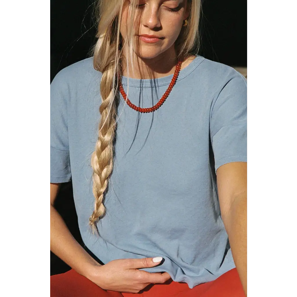 Woman in Petit Pointelle organic cotton tee with vibrant red beaded necklace