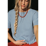 Woman in Petit Pointelle organic cotton tee with vibrant red beaded necklace