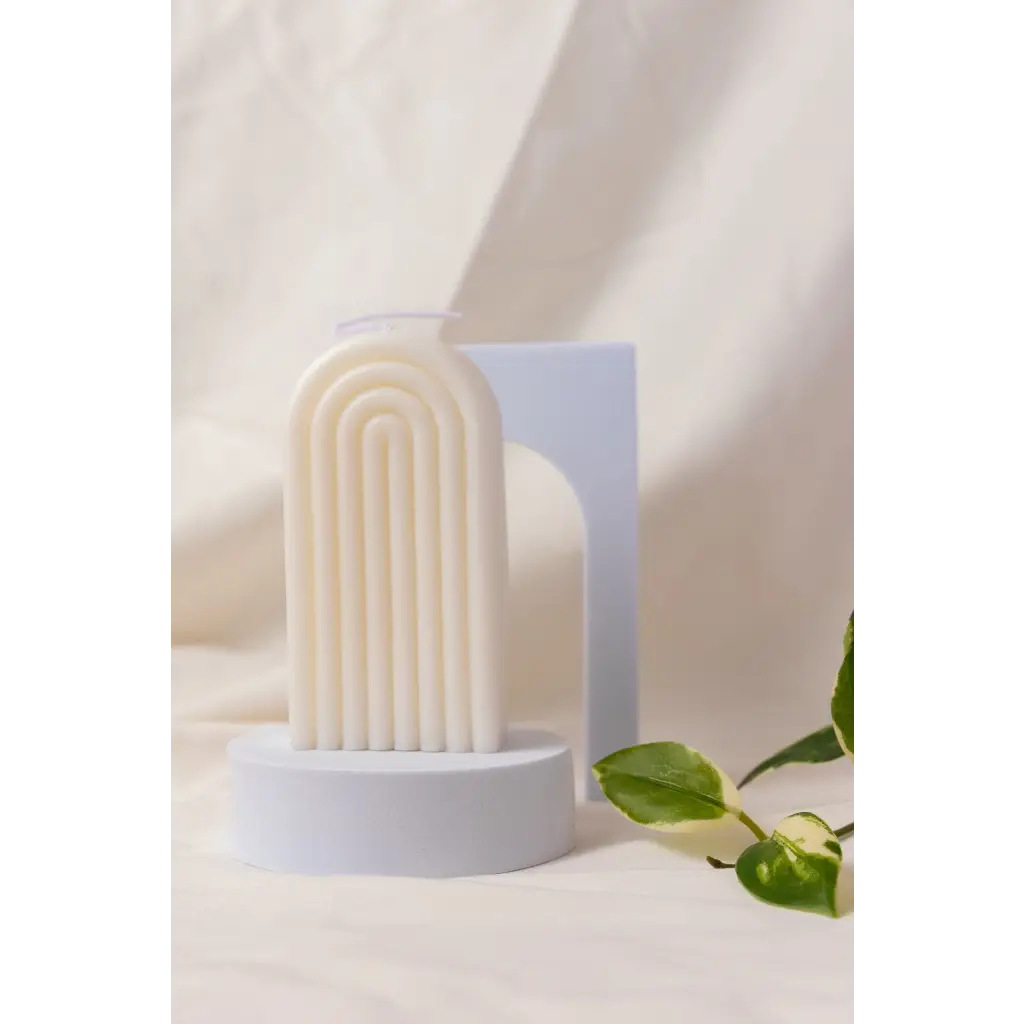 White ribbed arch-shaped Petite Rainbow Candle on a circular base for colorful decor