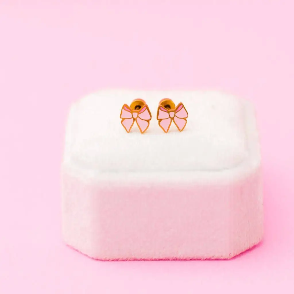 Pink bow stud earrings with gold accents in stylish womens clothes box