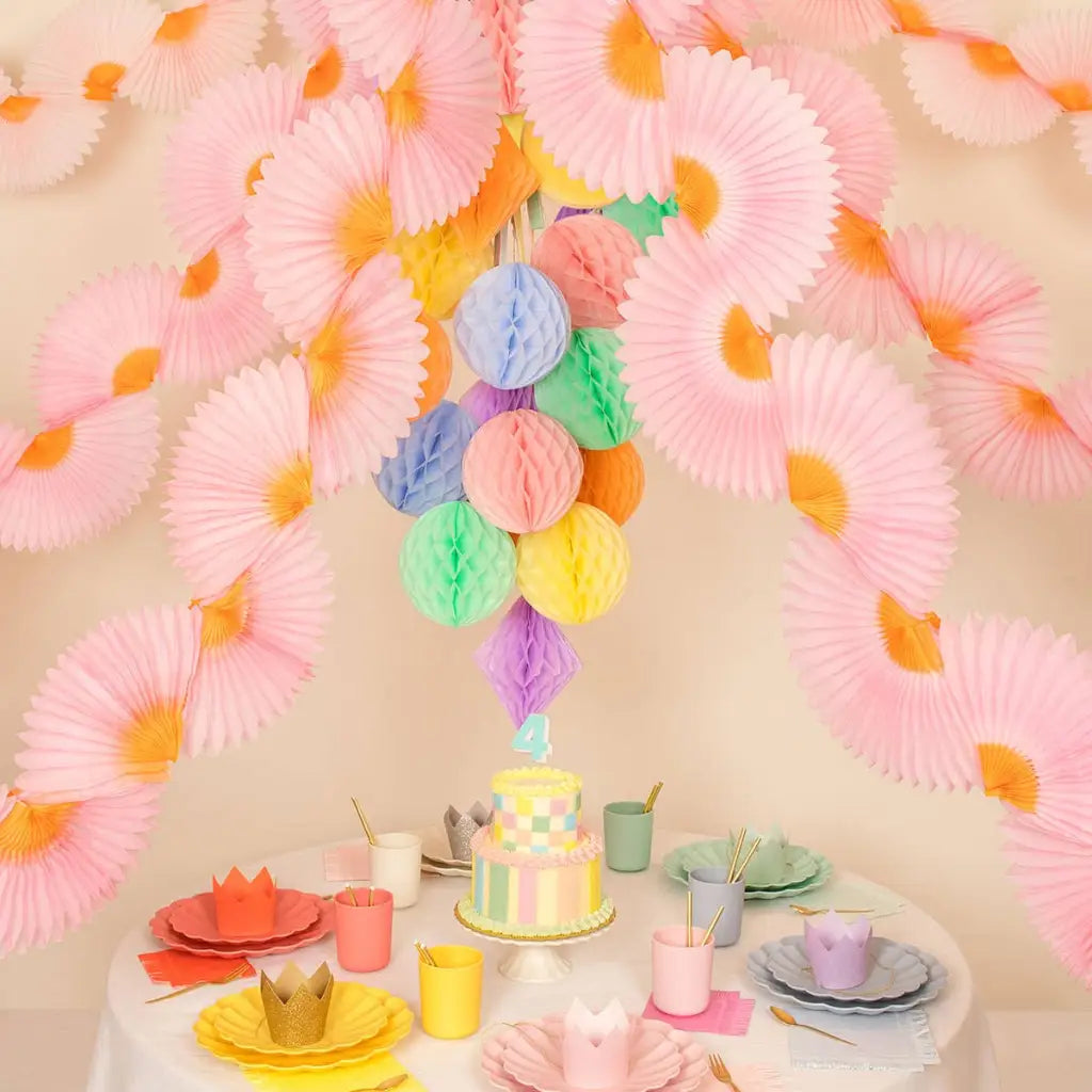 Pastel pom-poms hang from pink orange fans in Polished Prints garland