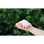 Hand holding a pink and white eraser next to a Bubble Gum Pink Sedan in Solid Beech Wood