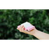 Hand holding a pink and white eraser next to a Bubble Gum Pink Sedan in Solid Beech Wood