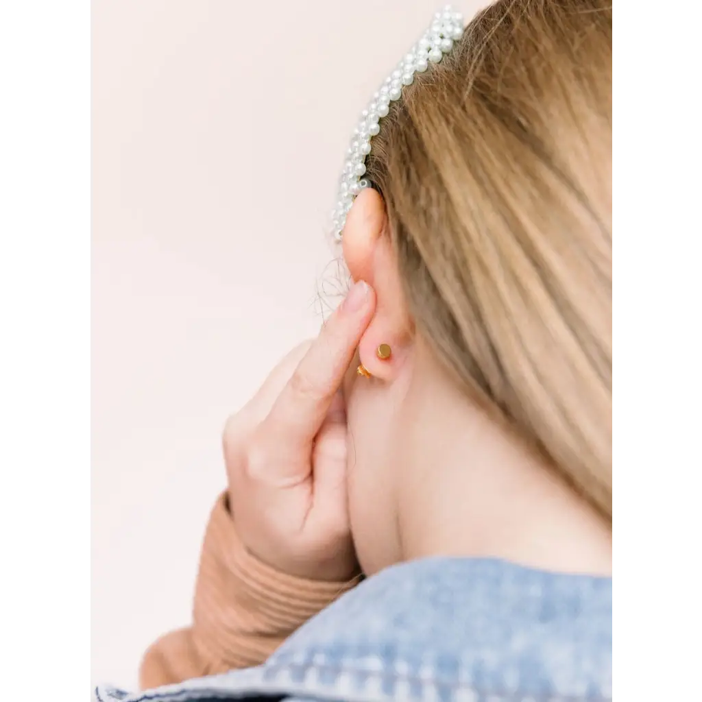 Hand touching an ear with a pearl earring, perfect hypoallergenic earrings for active girls