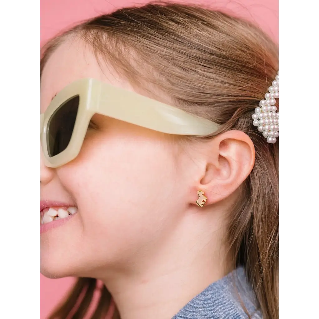 Cream-colored retro sunglasses next to hypoallergenic earrings for active girls with sensitive ears