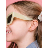 Cream-colored retro sunglasses next to hypoallergenic earrings for active girls with sensitive ears