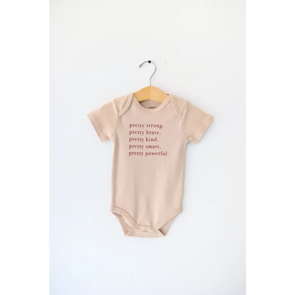 Tan baby onesie with empowering text made from Pretty Brave Organic Cotton