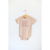 Tan baby onesie with empowering text made from Pretty Brave Organic Cotton