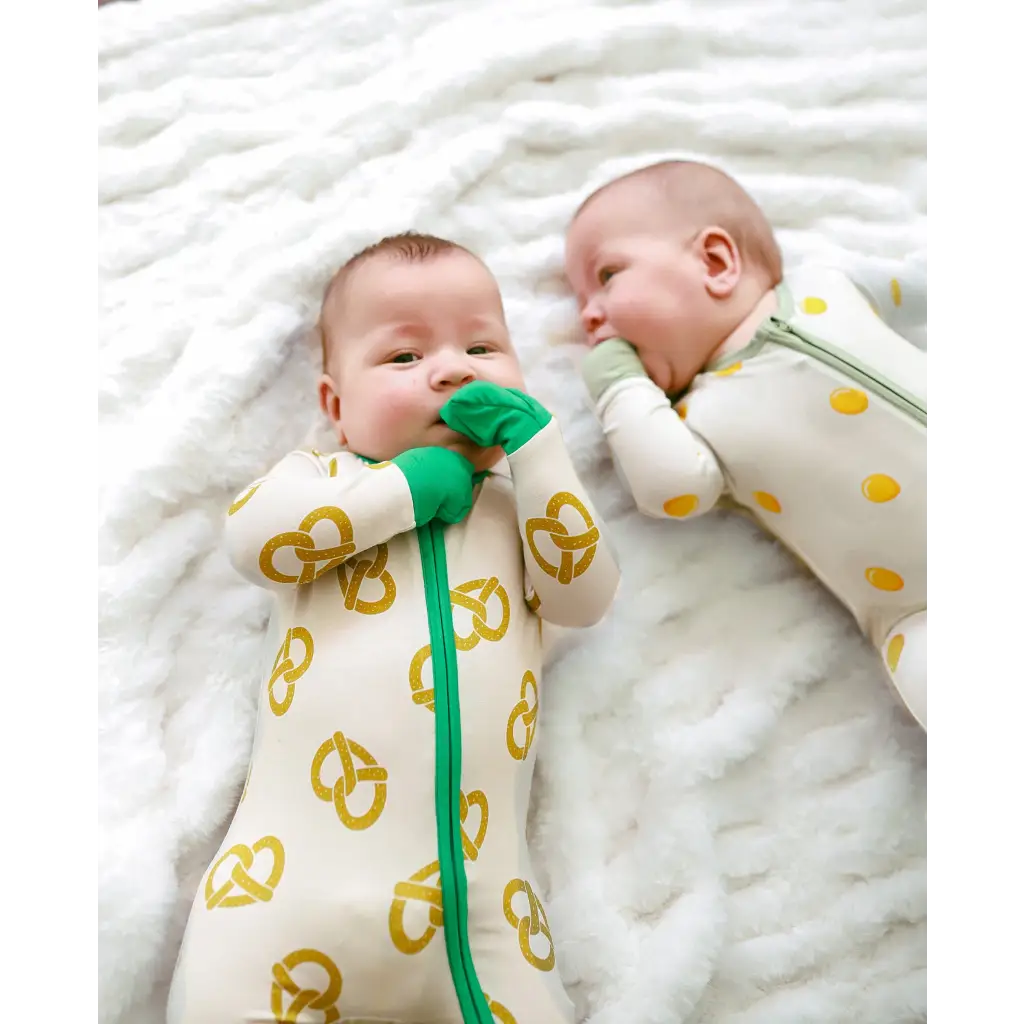 Two babies in matching Pretzel Party Bamboo Baby Sleepers for cozy nighttime fun