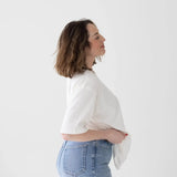 Side profile of someone wearing a white top and light blue jeans.