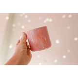 Hand holding a pink ceramic mug with a cute bow design, perfect campfire mug